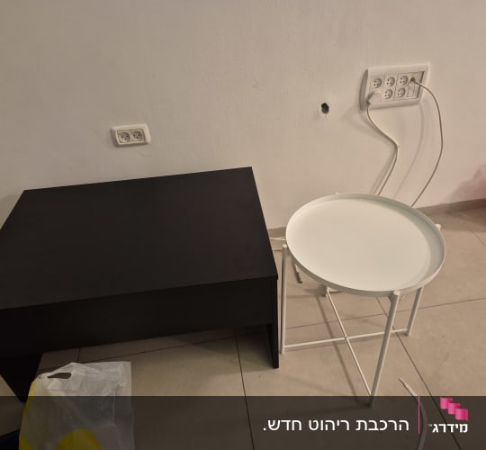 שולחן קפה שחור ושולחן צד לבן מורכבים בחדר